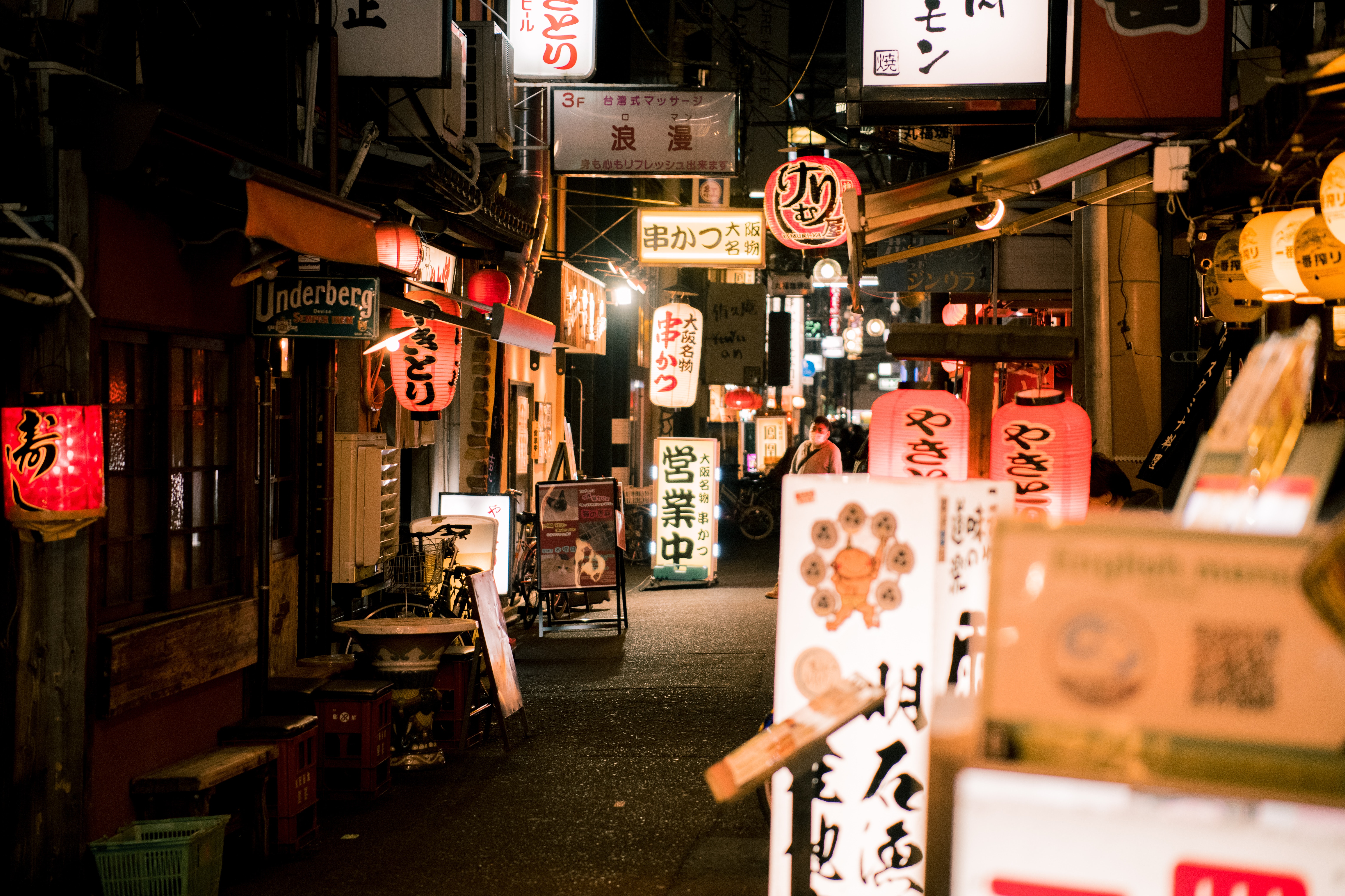 Traditional Japanese paper lanterns light up a small lane full of shops in Tokyo.